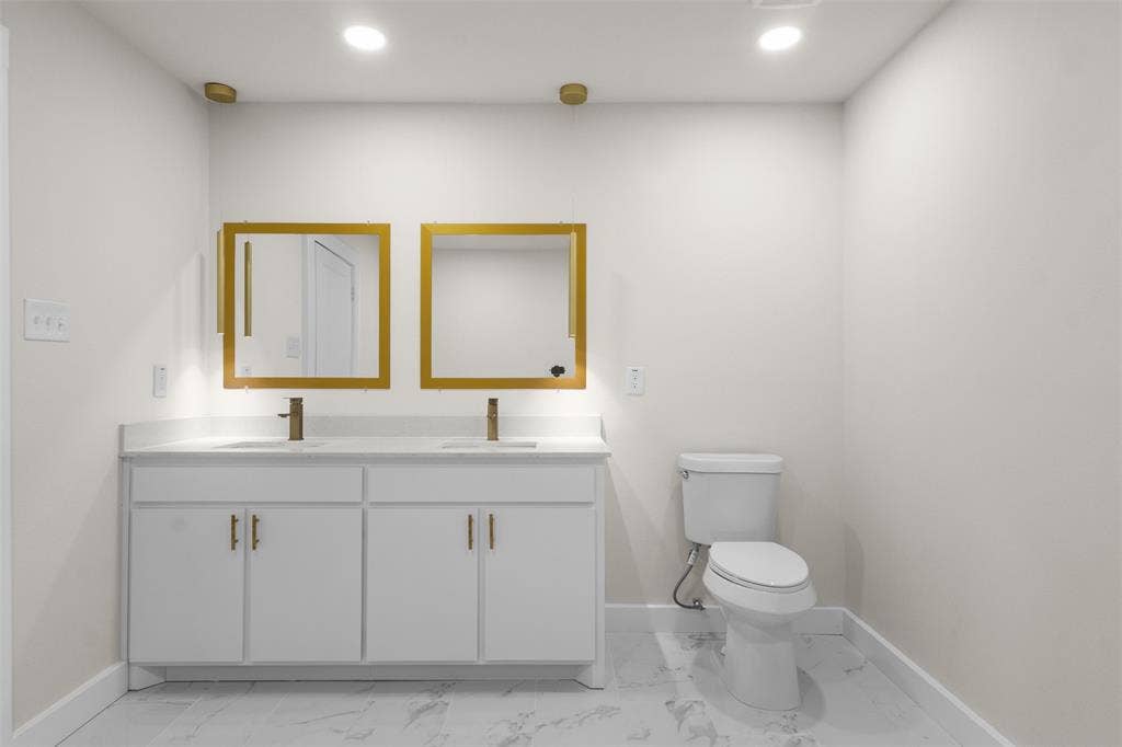 1507 E Waco Avenue, Dallas, TX 75216 Dual vanity with white cabinetry, gold-toned hardware, and rectangular under-mount sinks