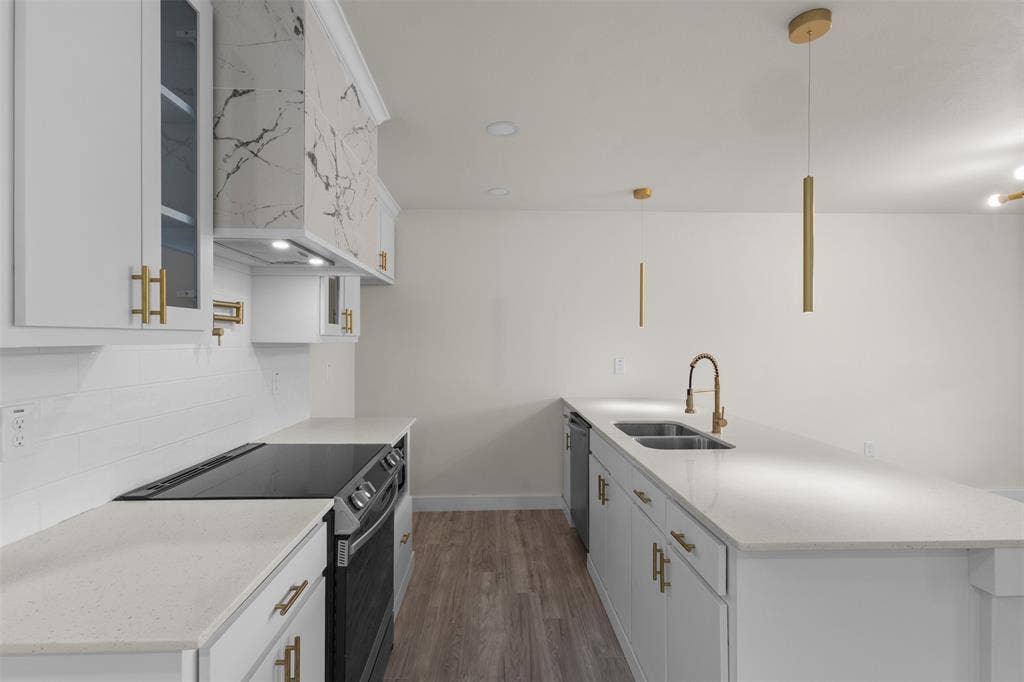 1507 E Waco Avenue, Dallas, TX 75216 Contemporary kitchen featuring white cabinetry with gold-tone hardware, a white subway tile backsplash, and light-toned countertops