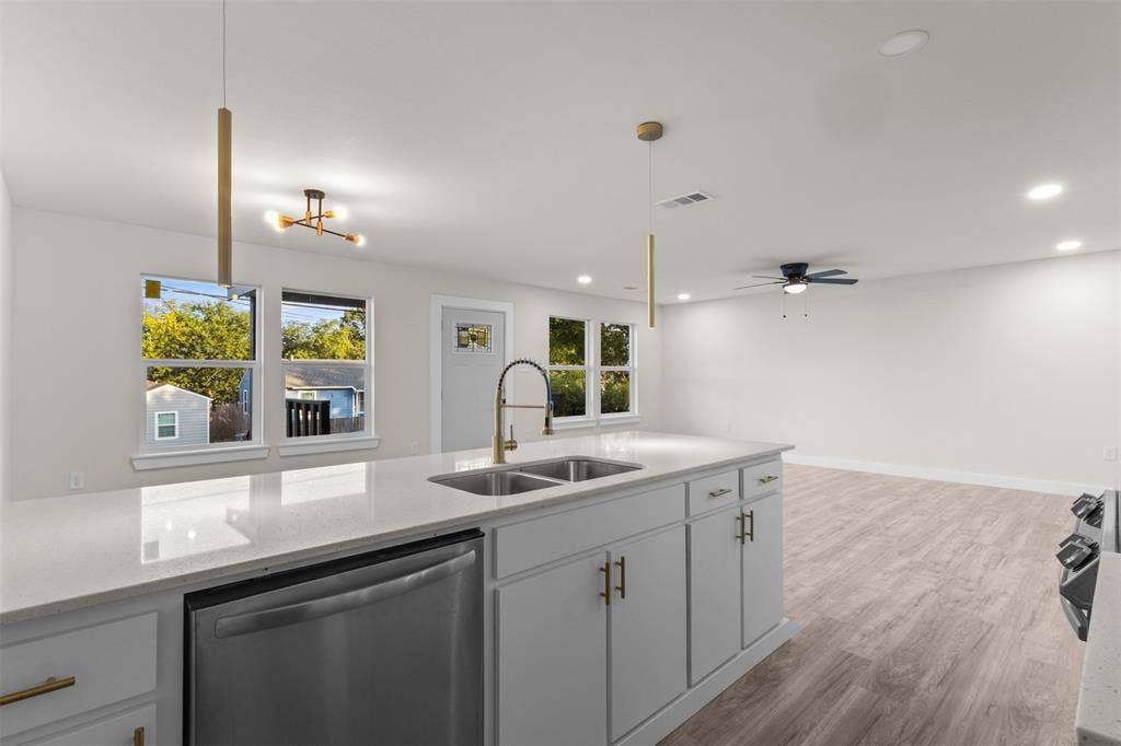 1507 E Waco Avenue, Dallas, TX 75216 Open-concept kitchen featuring a large island with a double basin sink, light-toned countertops, and contemporary pendant lighting