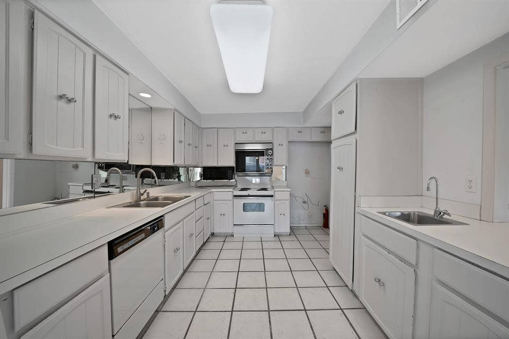 12574 Burninglog Lane, Dallas, TX 75243 Galley kitchen featuring extensive white cabinetry, white countertops, tile flooring, mirrored backsplash, and a double basin sink