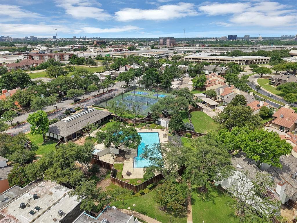 12574 Burninglog Lane, Dallas, TX 75243 Community amenities featuring a central swimming pool with surrounding lounge areas, two tennis courts, and a clubhouse building, all set amidst mature trees and residential structures