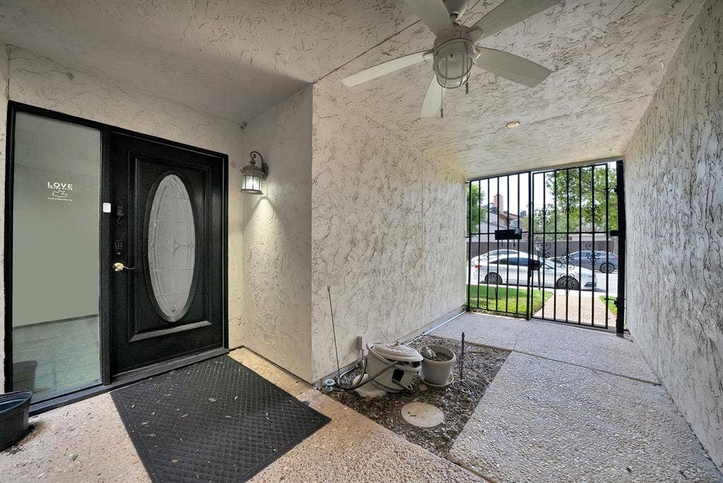 12574 Burninglog Lane, Dallas, TX 75243 Covered entryway featuring a black front door with an oval glass insert, an attached exterior light fixture, and a ceiling fan
