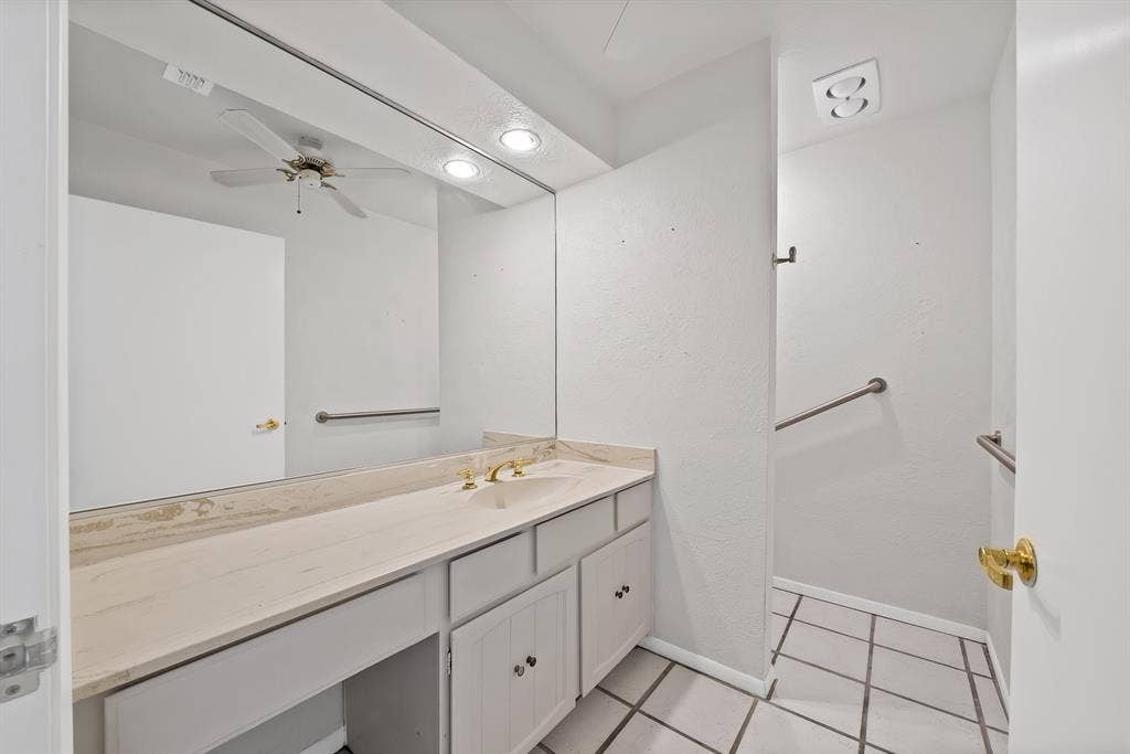 12574 Burninglog Lane, Dallas, TX 75243 Bathroom vanity featuring a light-toned countertop, undermount sink, and brass-finish faucet