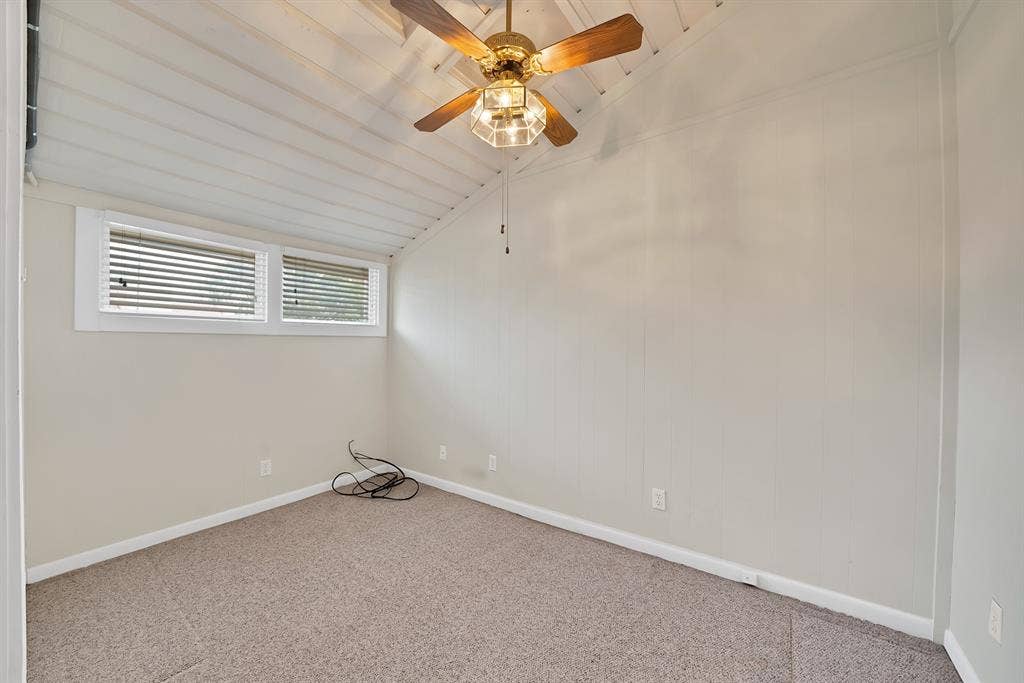 12574 Burninglog Lane, Dallas, TX 75243 Room featuring a vaulted ceiling with exposed white wood planks, a ceiling fan with integrated lighting, and a neutral-toned carpeted floor
