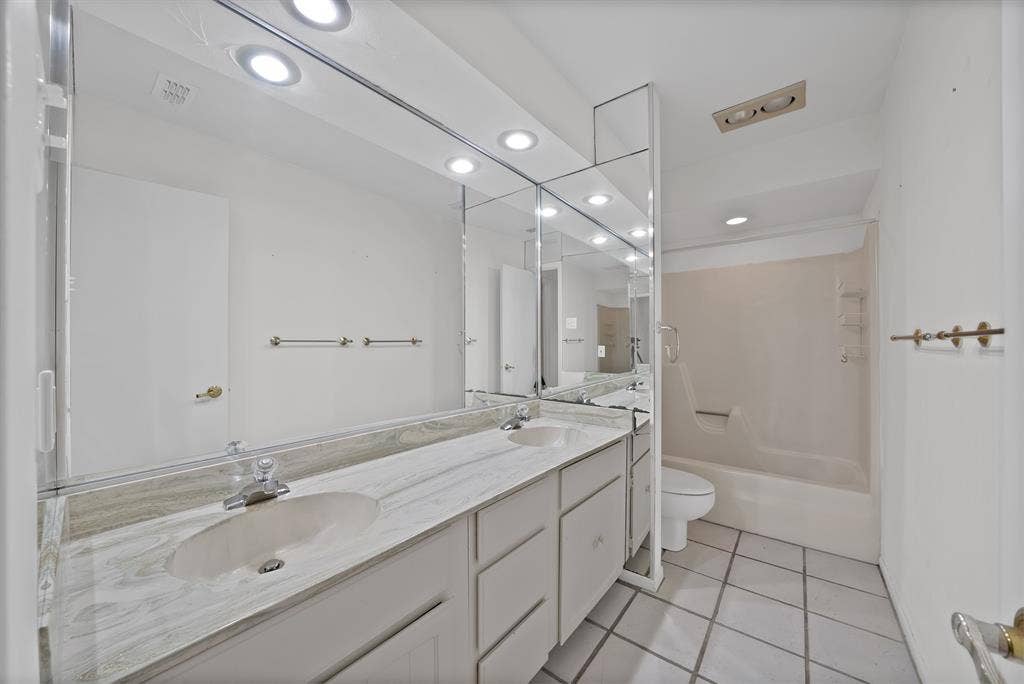 12574 Burninglog Lane, Dallas, TX 75243 Bathroom featuring a dual-sink vanity with a stone countertop, white cabinetry, and an integrated mirror with overhead lighting