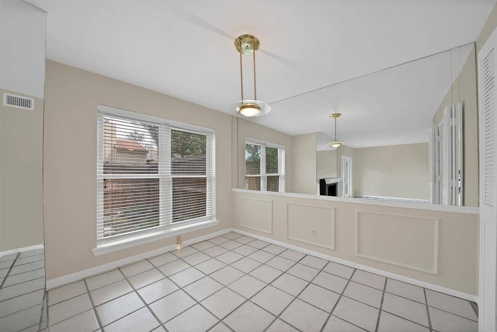 12574 Burninglog Lane, Dallas, TX 75243 Dining area featuring large window with blinds, overhead lighting fixture, tiled flooring, and a mirrored wall panel