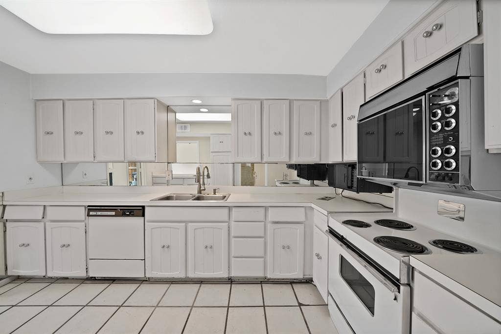 12574 Burninglog Lane, Dallas, TX 75243 Kitchen featuring white cabinetry with silver hardware, a white solid surface countertop, an undermount double basin sink with a gooseneck faucet, a built-in dishwasher, and an electric range with an overhead microwave