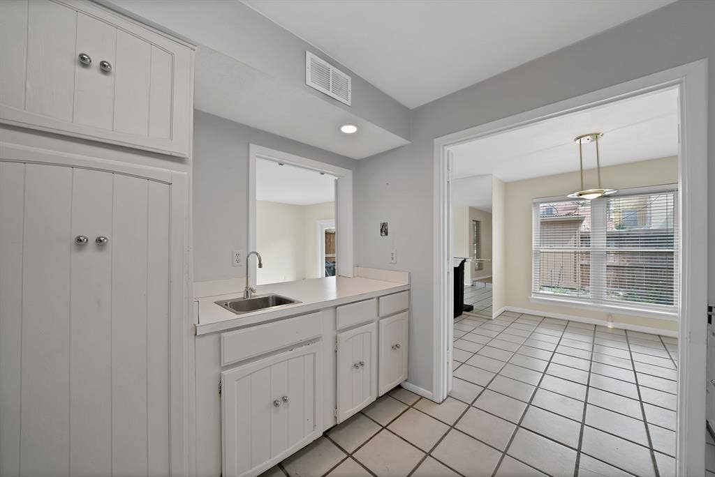12574 Burninglog Lane, Dallas, TX 75243 Kitchenette featuring a stainless steel sink with a gooseneck faucet, white cabinetry, and light-toned countertops