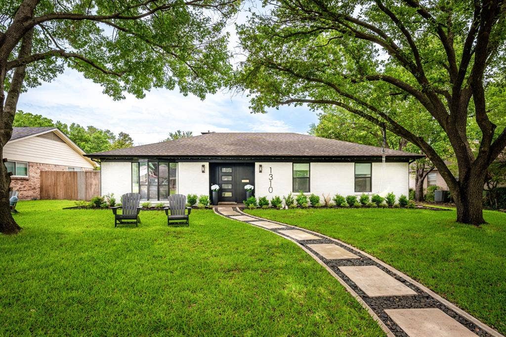 Single-story residence featuring a white exterior, dark trim, and a prominent black front door with horizontal glass panels