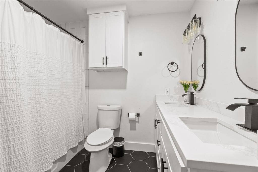 Bathroom featuring a dual vanity with undermount sinks, white countertops, and matte black fixtures