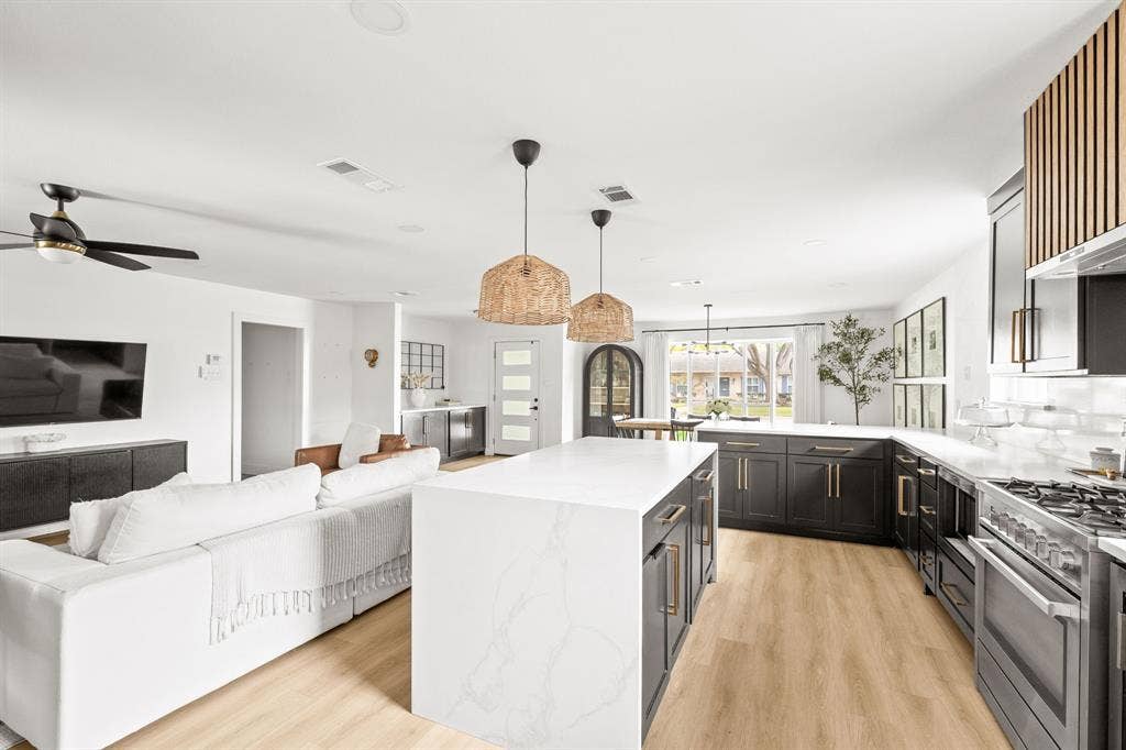 Open-concept living space featuring a gourmet kitchen with a central island, dark cabinetry, and light countertops