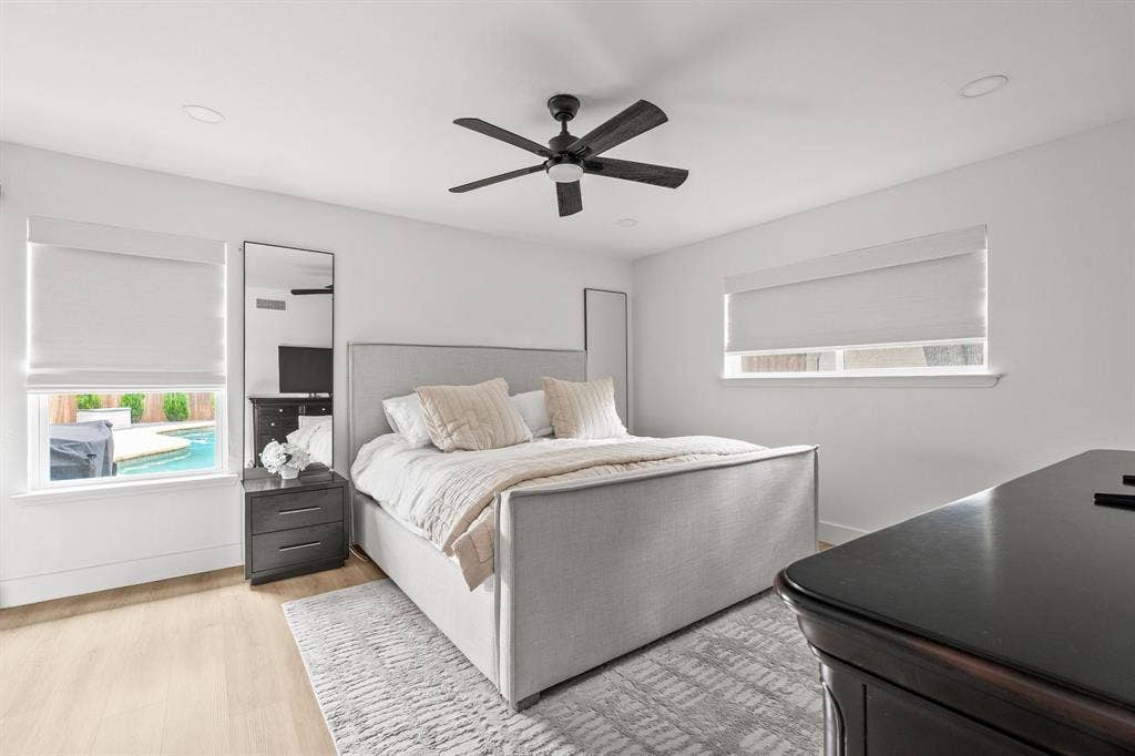 Bedroom featuring light wood-finish flooring, recessed lighting, and a dark-toned ceiling fan