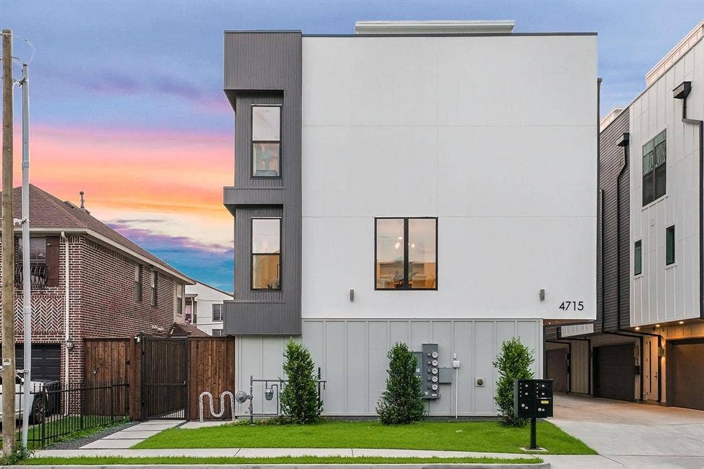4715 Manett Street, #102, Dallas, TX 75204 Modern multi-level residence featuring a white and gray facade, multiple windows, a manicured lawn, and a paved walkway