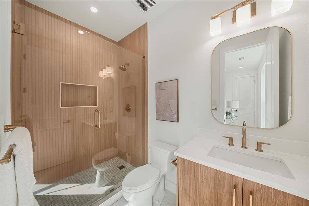 4715 Manett Street, #102, Dallas, TX 75204 Bathroom featuring a glass-enclosed shower with fluted wood-finish wall panels and a built-in niche