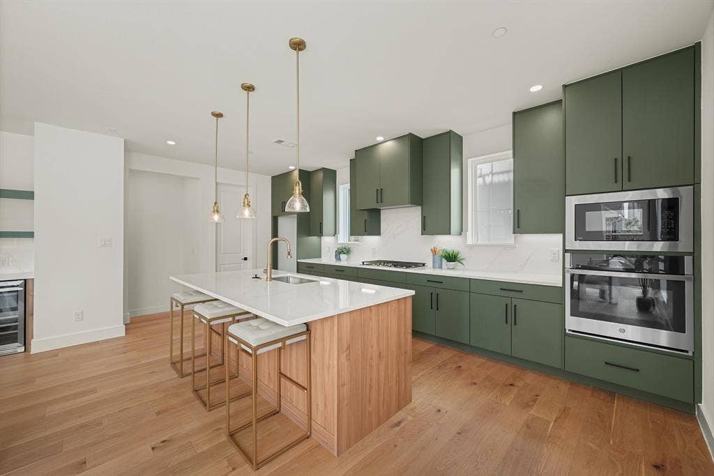 4715 Manett Street, #102, Dallas, TX 75204 Contemporary kitchen featuring a large central island with seating, a white countertop, and a built-in sink