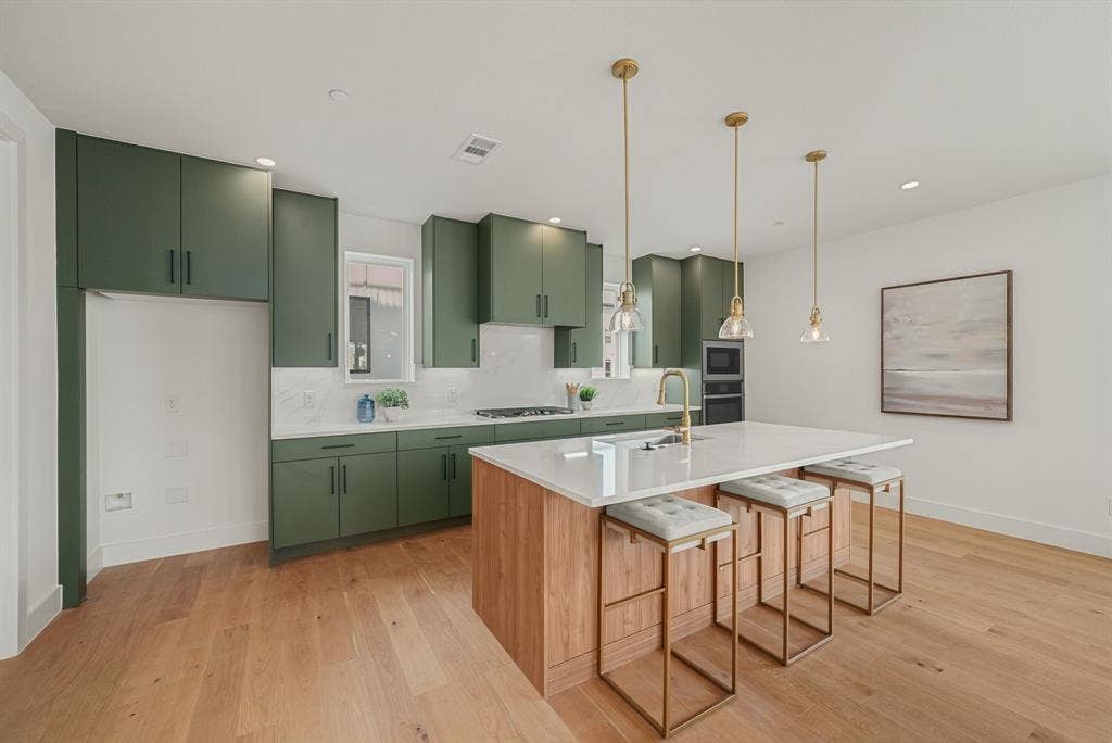 4715 Manett Street, #102, Dallas, TX 75204 Contemporary kitchen featuring olive green cabinetry, light wood-finish flooring, and a large center island with seating