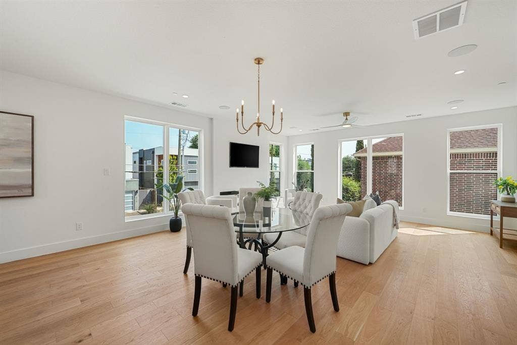 4715 Manett Street, #102, Dallas, TX 75204 Open-concept living space with light wood-finish flooring, numerous windows, and a modern chandelier
