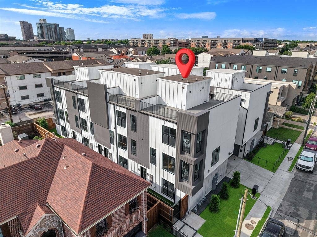 4715 Manett Street, #102, Dallas, TX 75204 Modern multi-story building featuring white and gray paneling, multiple balconies with black railings, and large windows