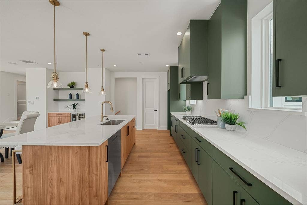 4715 Manett Street, #102, Dallas, TX 75204 Modern kitchen featuring a spacious island with wood-finish paneling, white countertops, and integrated sink