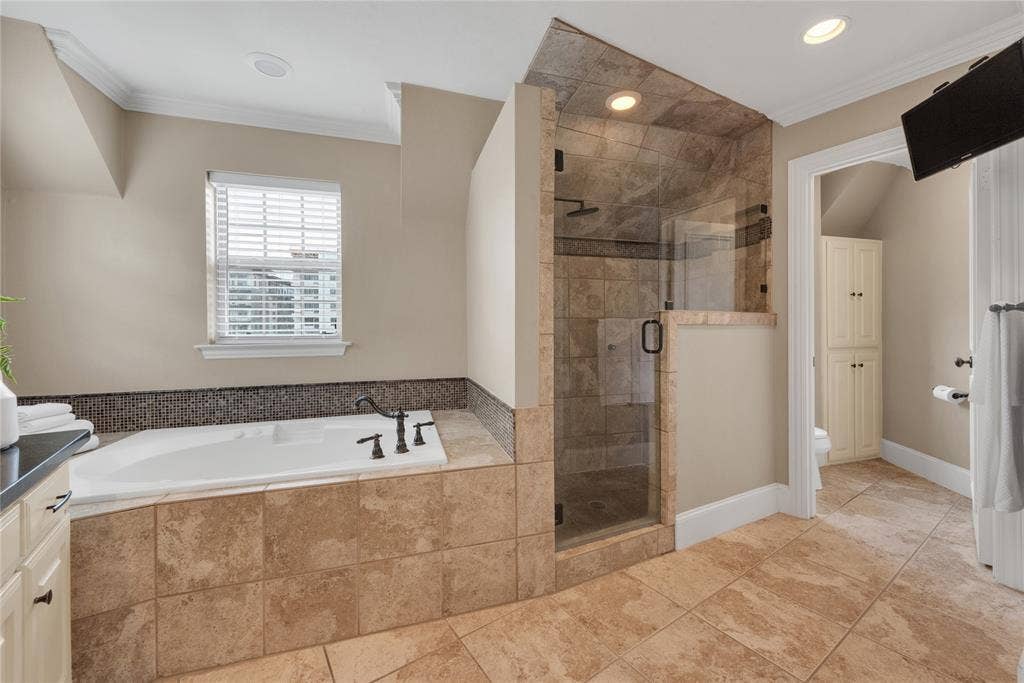 5102 Ridgedale Avenue, Dallas, TX 75206 Spacious bathroom featuring a built-in tub with dark bronze fixtures, a tiled surround, and a mosaic tile backsplash