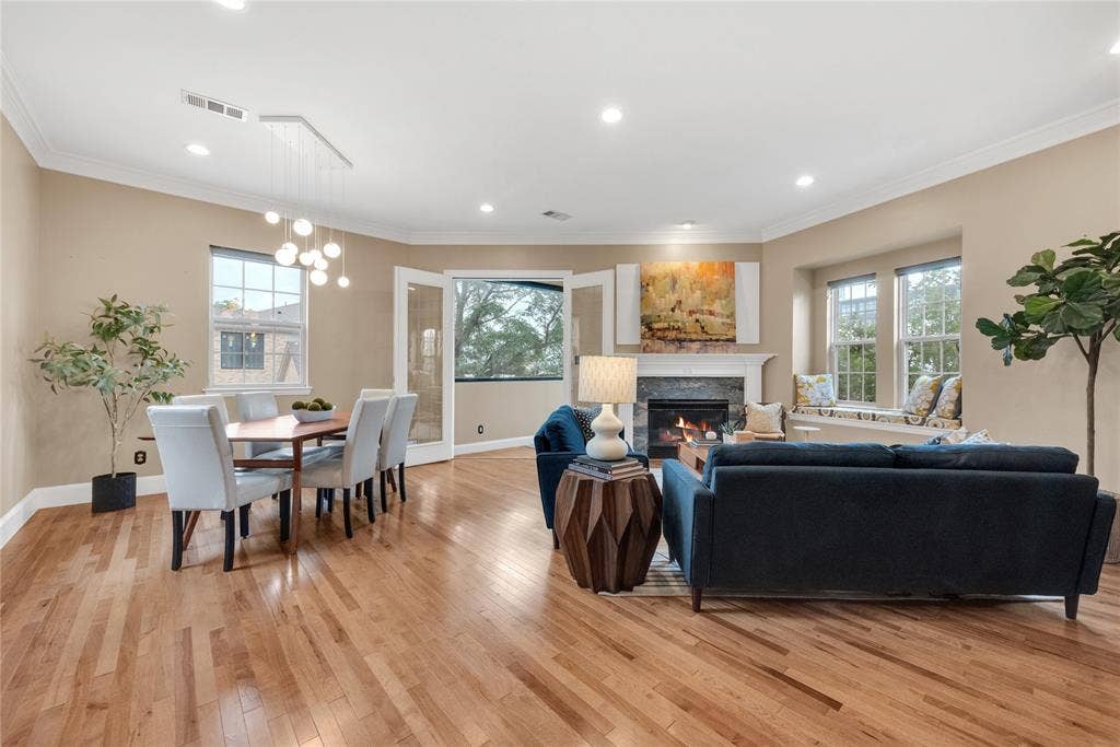 5102 Ridgedale Avenue, Dallas, TX 75206 Spacious living area featuring warm wood-finish flooring, a contemporary fireplace with a stone surround and white mantle, and recessed lighting