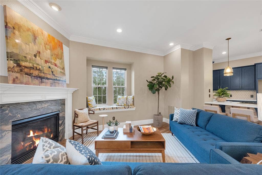 5102 Ridgedale Avenue, Dallas, TX 75206 Living area featuring a fireplace with a stone surround and a substantial mantel, recessed lighting, crown molding, a built-in window seat, and wood-finish flooring