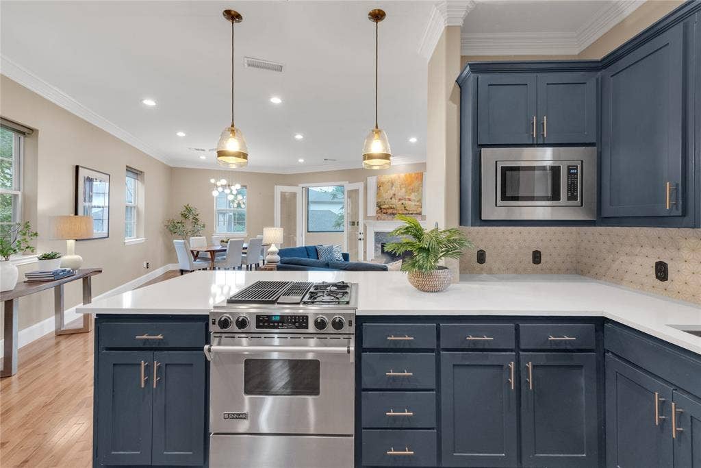 5102 Ridgedale Avenue, Dallas, TX 75206 Kitchen featuring a stainless steel range with a gas cooktop, white countertops, dark blue cabinetry with brushed nickel hardware, a built-in microwave, and a textured tile backsplash