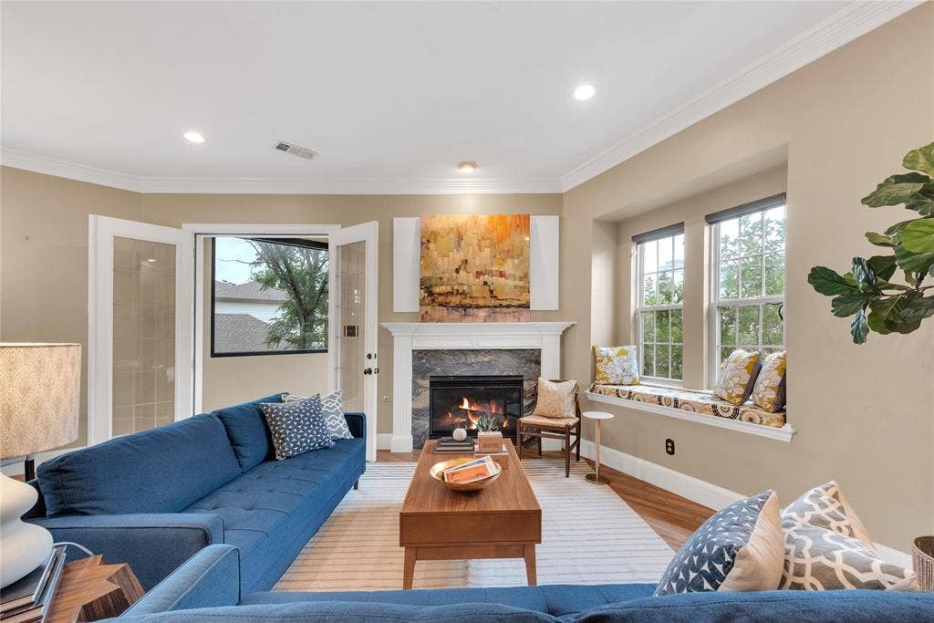 5102 Ridgedale Avenue, Dallas, TX 75206 Living room featuring a fireplace with stone surround and white mantel, hardwood flooring, and a window seat with cushion