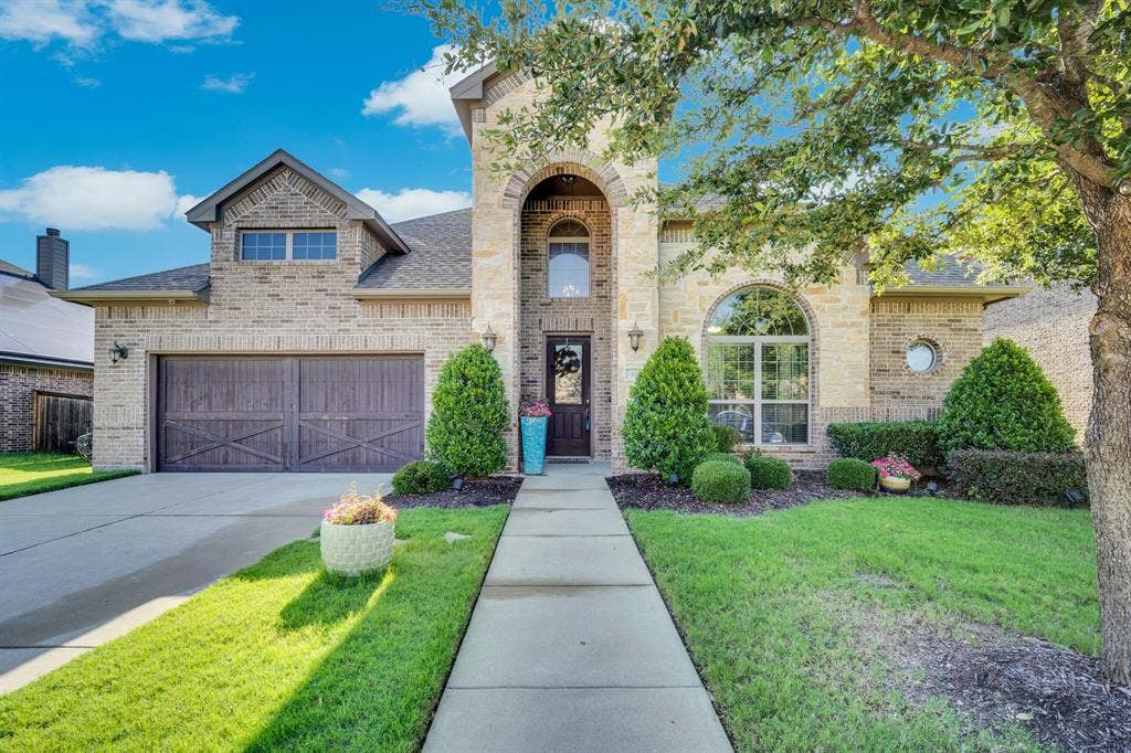 Front of home with 2-car garage, lots of windows, and beautiful landscaping.