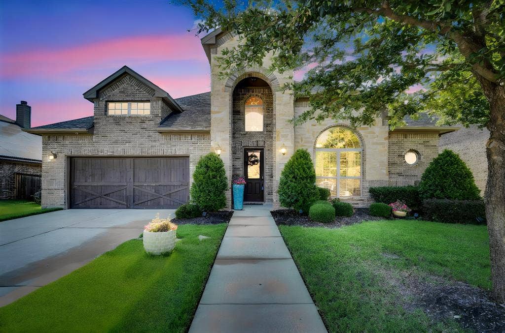 Front of home with 2-car garage, lots of windows, and beautiful landscaping.