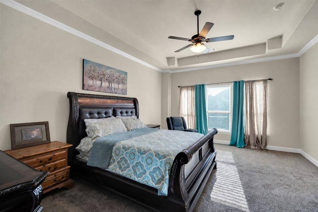 Primary bedroom featuring tons of natural light, high ceilings, and ceiling fan and crown molding.