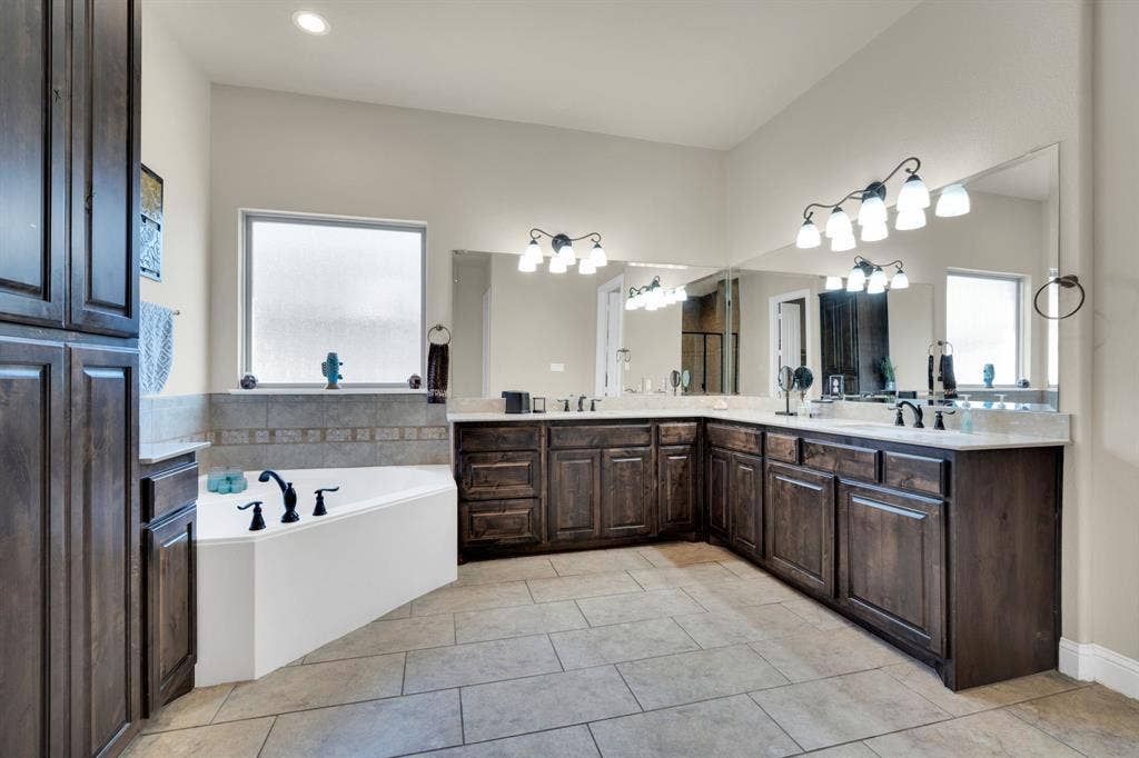 Primary bathroom with dual sinks, garden tub, and beautiful cabinetry and natural light.