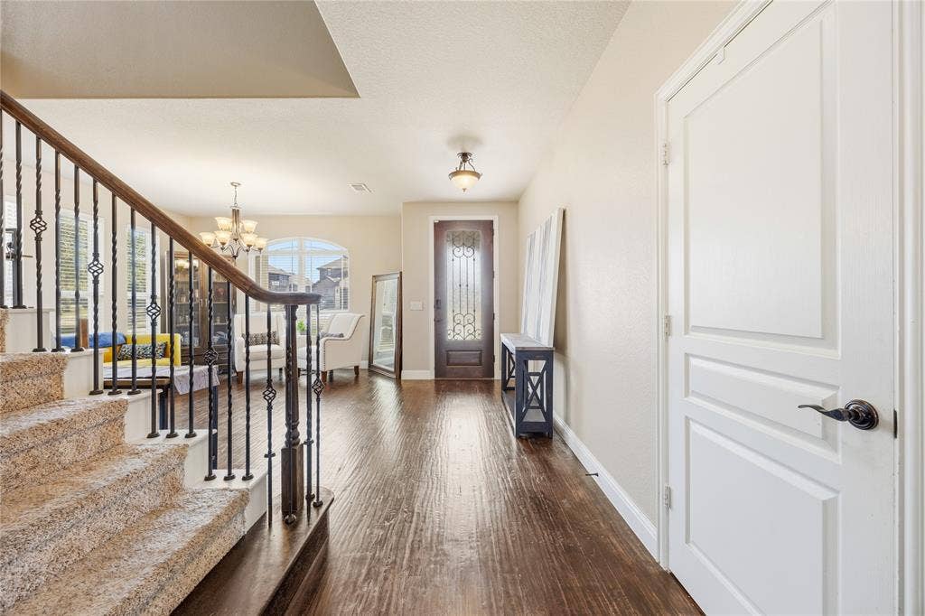 1133 Vickery Drive, DeSoto, TX 75115 Foyer featuring rich wood-finish flooring, a decorative glass-paneled entry door, and a carpeted staircase with wrought iron balusters