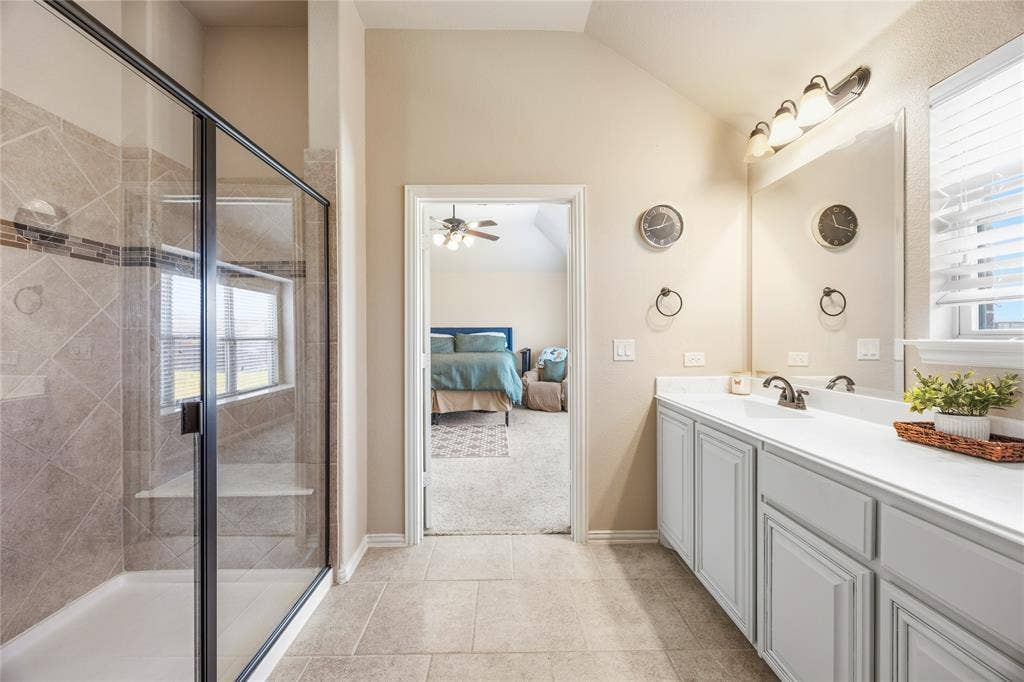 1133 Vickery Drive, DeSoto, TX 75115 2nd floor primary bathroom two. Spacious bathroom featuring a glass-enclosed shower with tile surround and built-in bench, vanity with undermount sinks, and a large mirror