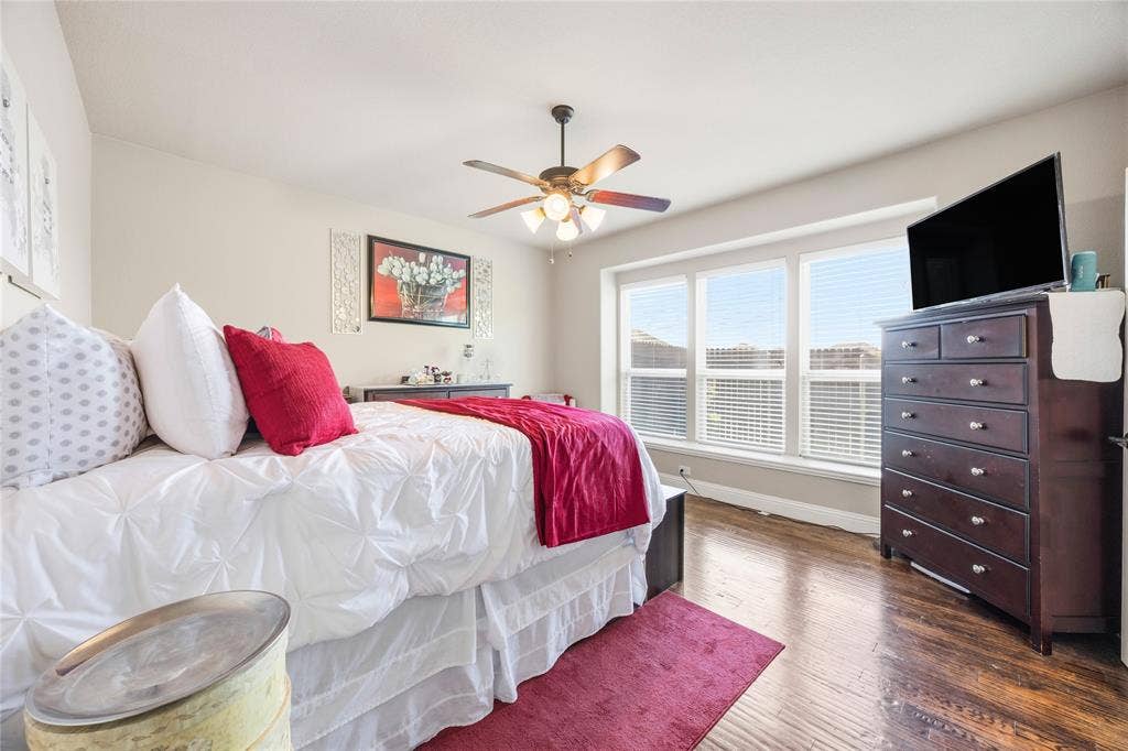 1133 Vickery Drive, DeSoto, TX 75115 1st floor Primary Bedroom one featuring a multi-pane window, wood-finish flooring, and a ceiling fan with integrated lighting