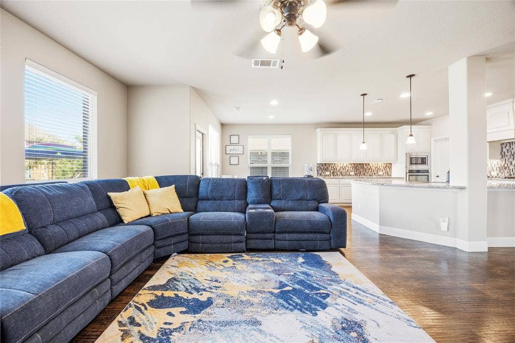 1133 Vickery Drive, DeSoto, TX 75115 Open-concept living area featuring wood-finish flooring, a ceiling fan with integrated lighting, and multiple windows