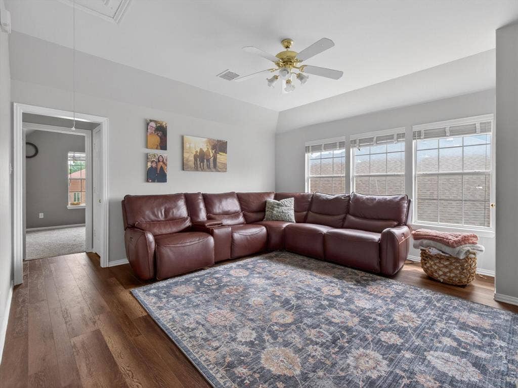 1712 Tealwood Lane, Corinth, TX 76210 Spacious living area featuring wood-finish flooring, a tray ceiling, and a ceiling fan with integrated lighting