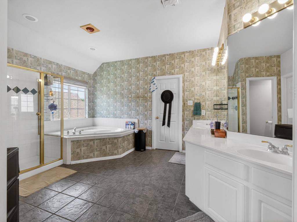 1712 Tealwood Lane, Corinth, TX 76210 Spacious bathroom featuring a built-in corner soaking tub, a walk-in shower with gold-tone framing, and a double vanity with ample counter space