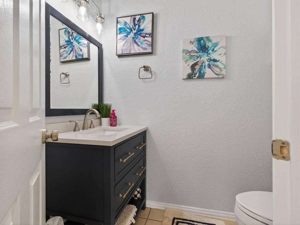 1712 Tealwood Lane, Corinth, TX 76210 Powder room featuring a dark blue vanity with a white countertop and integrated sink, brushed nickel faucet, and a framed mirror with overhead lighting