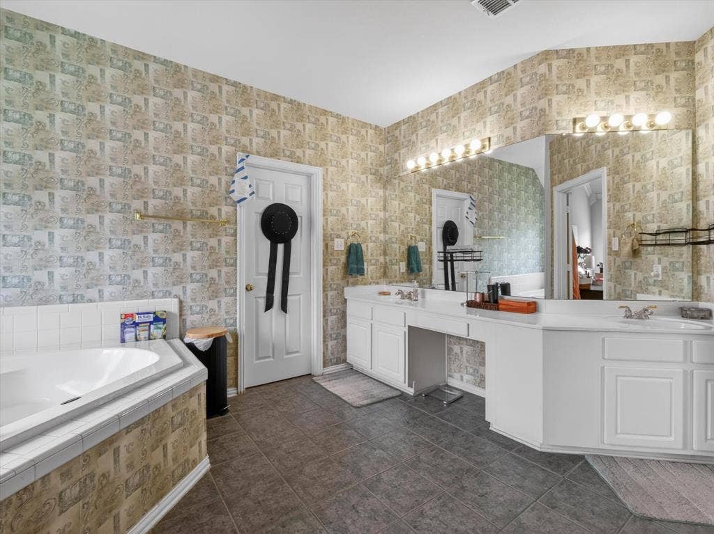 1712 Tealwood Lane, Corinth, TX 76210 Bathroom featuring a built-in corner soaking tub, dual vanity with white cabinetry, and large wall-mounted mirrors