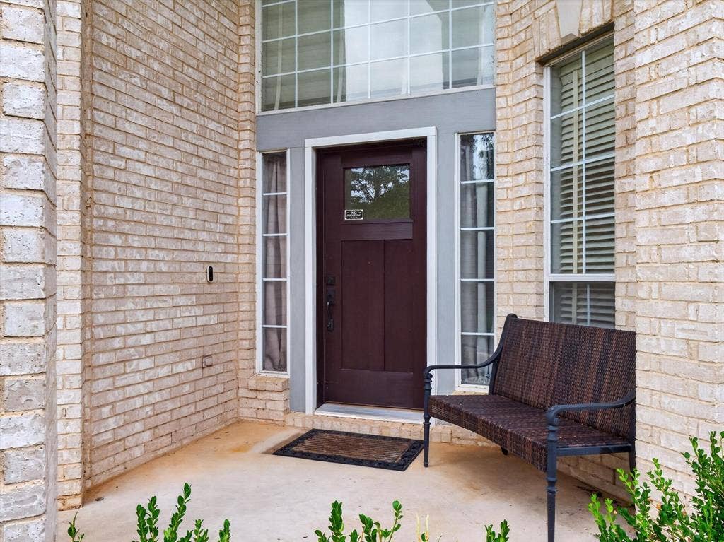 1712 Tealwood Lane, Corinth, TX 76210 Entryway featuring light-toned brickwork, a dark wood-finish door with sidelights, and a transom window