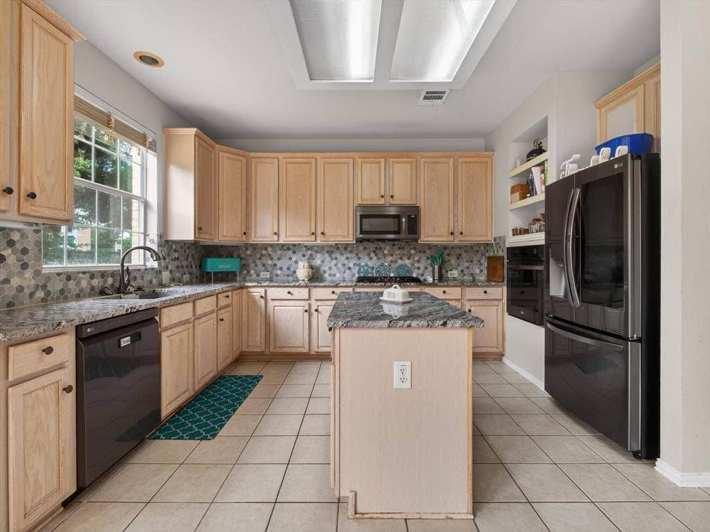 1712 Tealwood Lane, Corinth, TX 76210 Kitchen featuring light wood cabinetry, a central island, tile flooring, built-in appliances, and a mosaic tile backsplash
