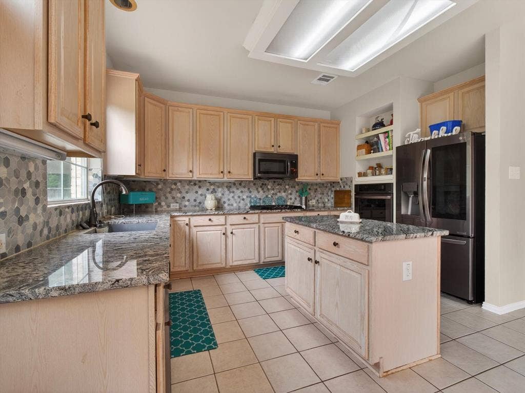 1712 Tealwood Lane, Corinth, TX 76210 Spacious kitchen featuring light wood cabinetry, a mosaic tile backsplash, and granite countertops