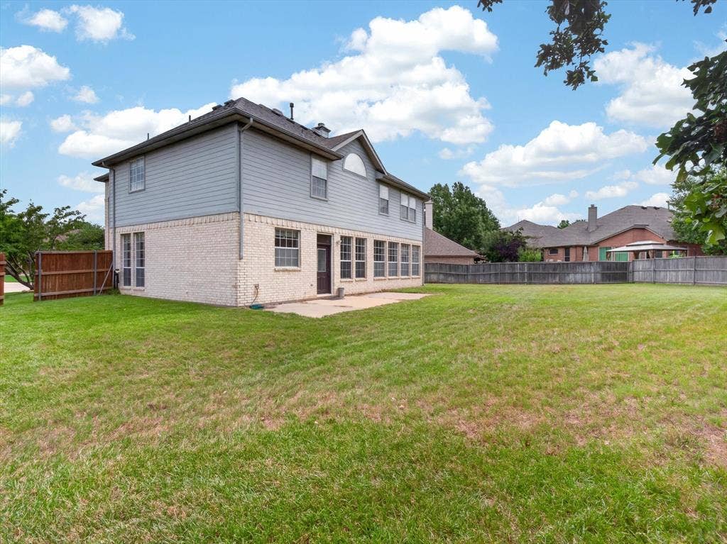 1712 Tealwood Lane, Corinth, TX 76210 Expansive backyard featuring a large grass lawn, perimeter wood fencing, and a concrete patio