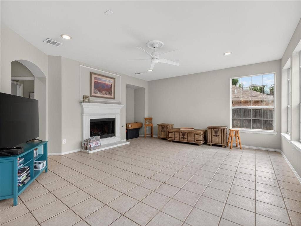 1712 Tealwood Lane, Corinth, TX 76210 Living area featuring tiled flooring, a fireplace with a white mantel, an arched entryway, multiple windows, and recessed lighting