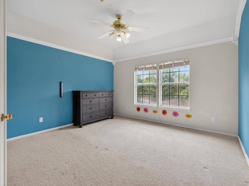 1712 Tealwood Lane, Corinth, TX 76210 Carpeted room featuring a vaulted ceiling with a ceiling fan, crown molding, and dual windows