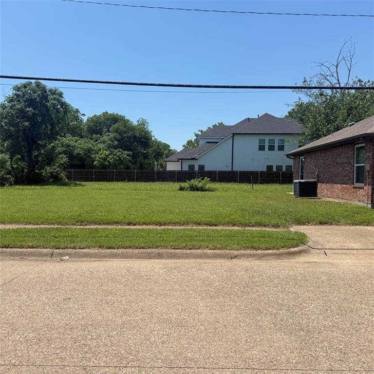 1902 Angelina Drive, Dallas, TX 75212 Expansive level lot featuring green grass, a concrete curb, and a partial privacy fence at the rear