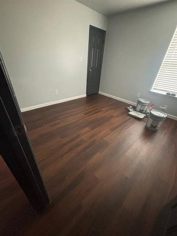1902 Angelina Drive, Dallas, TX 75212 Spacious room featuring wood-finish flooring, light grey walls, white baseboards, and a dark paneled door
