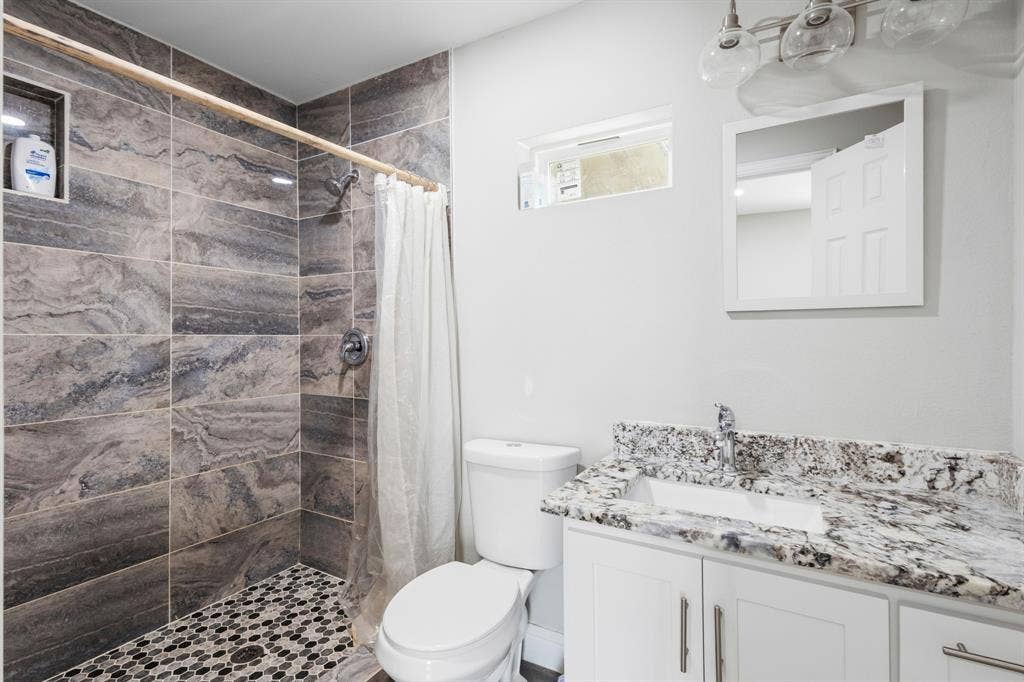 2006 Fort Worth Street, Grand Prairie, TX 75050 Bathroom featuring a tiled shower with mosaic pebble flooring, a built-in shower niche, and chrome fixtures