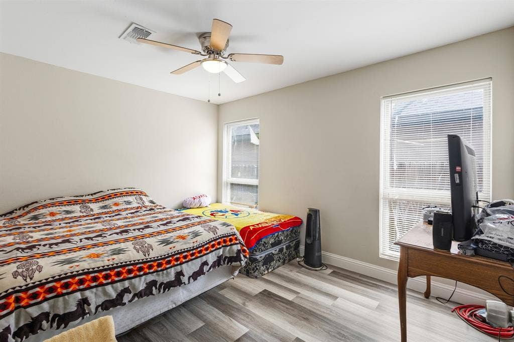 2006 Fort Worth Street, Grand Prairie, TX 75050 Interior space featuring wood-finish flooring, two windows with blinds, a ceiling fan with integrated lighting, and neutral wall tones